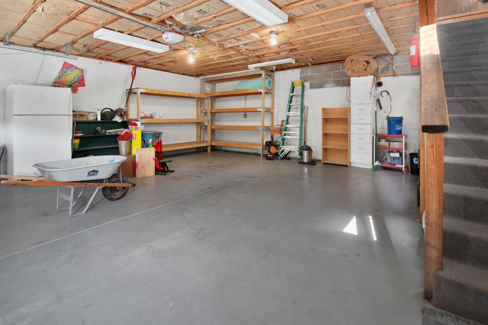 Spacious garage interior with storage shelves, tools, and a wheelbarrow, ideal for home organization.